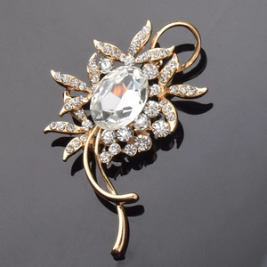 Macro d'une broche fleur dorée ornée de cristaux scintillants et d'une pierre centrale ovale