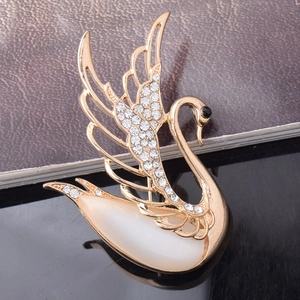 Close-up detail of golden swan brooch featuring white opal stone and sparkling zircon pavé