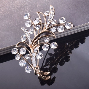 Gros plan d'une broche fleur dorée avec strass étincelants et reflet sur fond noir