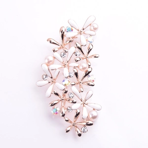 Détail macro d'une broche fleurie en émail blanc avec finition or rose et perles