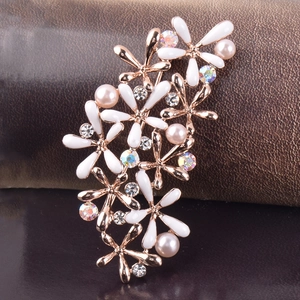 Détail de broche fleur or rose avec pétales en émail, perles et strass colorés brillants