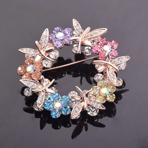 Macro shot of rose gold butterfly wreath brooch with colorful rhinestones on black background