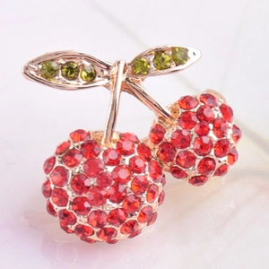 Detailed macro view of vibrant red crystal cherry brooch with gold alloy and green leaves