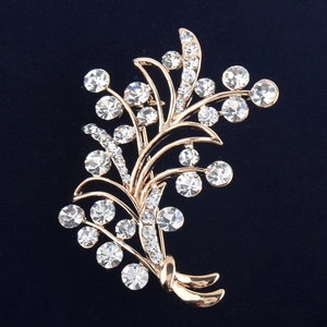 Détail d'une broche fleur dorée ornée de cristaux scintillants sur velours noir
