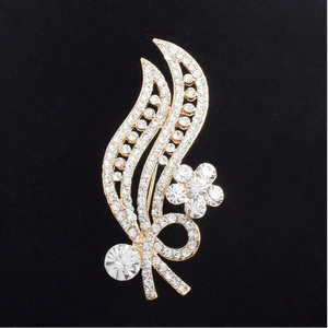 Elegant gold leaf brooch with rhinestones and flower detail on a sleek black background