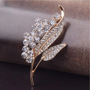 Elegant gold flower brooch with sparkling crystals and rhinestones on leather background