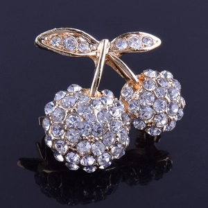 Detailed macro view of cherry brooch with gold alloy base and inlaid white crystals