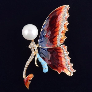 Detailed close-up of butterfly brooch with colorful enamel, rhinestones and large pearl