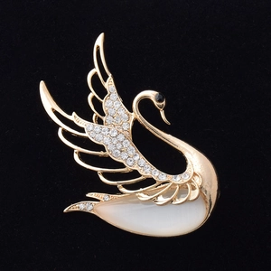 Detailed close-up of a golden swan brooch with cat eye stone and sparkling crystals
