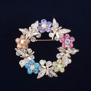 Detail shot of golden floral wreath brooch featuring colorful rhinestones on black velvet