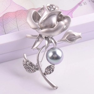 Détail de la broche rose en argent mat avec perle grise et feuilles serties de cristaux