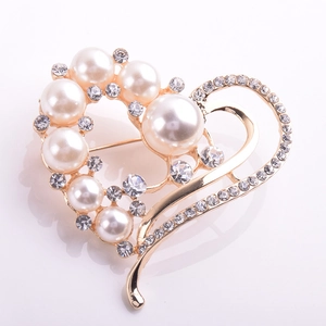 Détail d'une broche en forme de cœur avec perles blanches et cristaux sur monture dorée