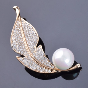 Broche élégante en forme de feuille dorée avec cristaux blancs et perle sur fond noir