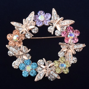 Macro shot of wreath brooch with colorful crystal flowers and sparkling dragonflies