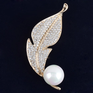 Broche élégante en forme de feuille dorée avec cristaux et perle blanche sur velours