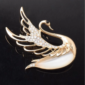 Elegant gold swan brooch with sparkling crystals and white shell opal inlay on black mirror