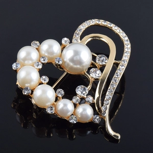 Élégante broche cœur dorée avec perles blanches et cristaux brillants sur fond noir