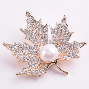 Detailed view of maple leaf brooch with sparkling rhinestones and a white pearl accent