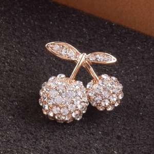Macro shot of twin cherry brooch with gold metal base and sparkling white rhinestones