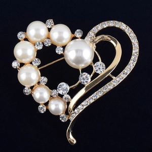 Gros plan d'une broche coeur dorée avec perles blanches et strass étincelants
