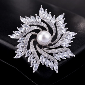 Macro shot of silver windmill brooch with a large central pearl and sparkling cubic zirconia