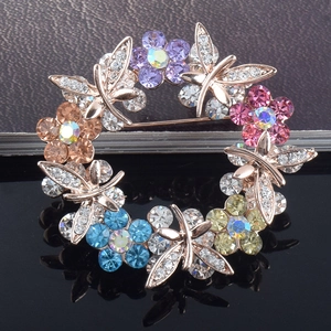 Macro shot of circular brooch featuring multi-colored crystal flowers and silver butterflies