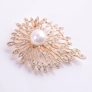 Détail macro d'une broche soleil avec perle blanche et pétales en zircon sur métal doré