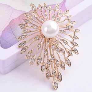 Détail d'une broche fleur dorée ornée d'une perle blanche et de cristaux brillants