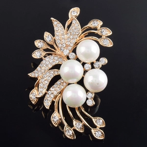 Détail d'une élégante broche fleur plaquée or avec perles blanches et strass brillants