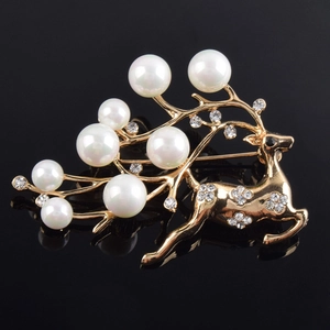 Exquisite gold reindeer brooch with white pearls and sparkling crystals on black background