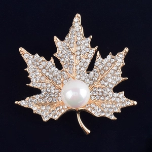 Elegant maple leaf brooch with sparkling rhinestones and a white pearl on a golden base