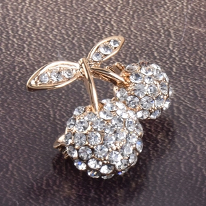 Macro shot of sparkling crystal cherry brooch with gold alloy base on leather surface