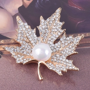 Elegant maple leaf brooch with sparkling rhinestones and a white pearl on golden base