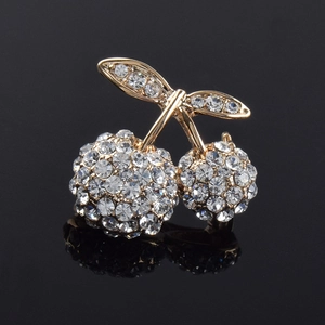 Macro shot of dual cherry brooch with gold metal and sparkling white crystals