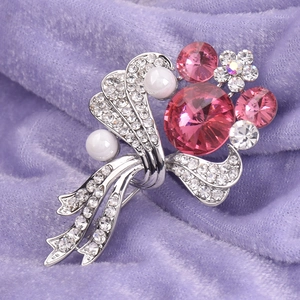Macro detail of elegant pink crystal floral brooch with pearls on purple velvet background
