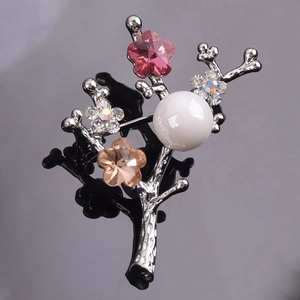 Elegant branch-shaped brooch with colorful crystals and large white pearl on a silver stem