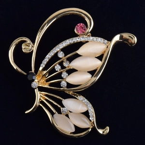 Élégante broche papillon dorée avec pierres œil de chat et strass sur velours noir