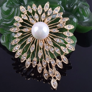 Détail macro d'une broche en perles avec feuilles rayonnantes et pierres en zircon clair