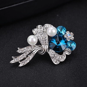 Detailed macro view of silver flower brooch with deep blue crystal and white pearls