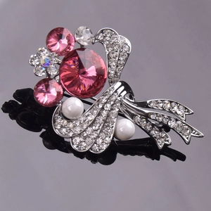 Macro view of crystal flower brooch with pink crystals and pearls on black surface