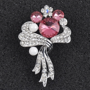 Macro shot of elegant pink crystal brooch with white pearls and silver ribbon base