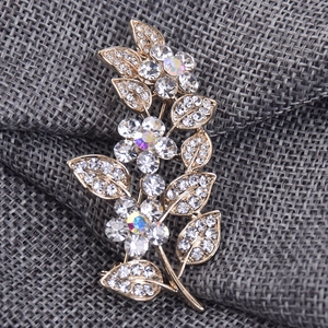 Détail macro d'une broche feuille avec strass AB étincelants sur base dorée florale