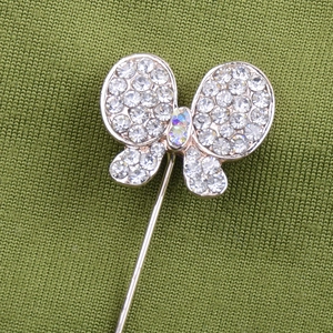 Gros plan d'une broche papillon avec strass blancs et gemmes sur tissu vert