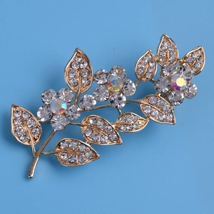 Détail macro d'une broche feuille de luxe avec cristaux étincelants sur base dorée