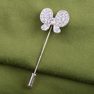 Broche papillon étincelante avec strass et longue épingle sur un tissu vert