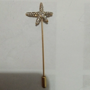 Macro shot of gold starfish lapel pin with sparkling rhinestones and metal pin cap