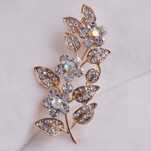Macro d'une broche fleur dorée avec feuilles et cristal central scintillant AB