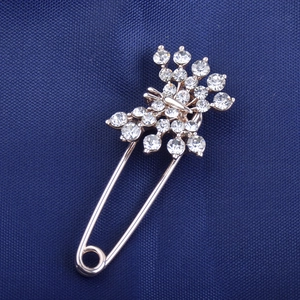 Close-up of safety pin brooch with sparkling crystals in rose gold finish on navy fabric