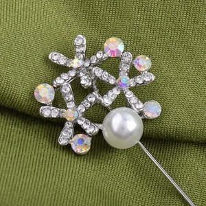 Broche fleur argentée élégante avec perles et cristaux brillants sur tissu vert