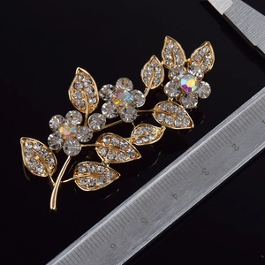 Vue détaillée d'une broche feuille en cristal avec strass irisés et finition dorée